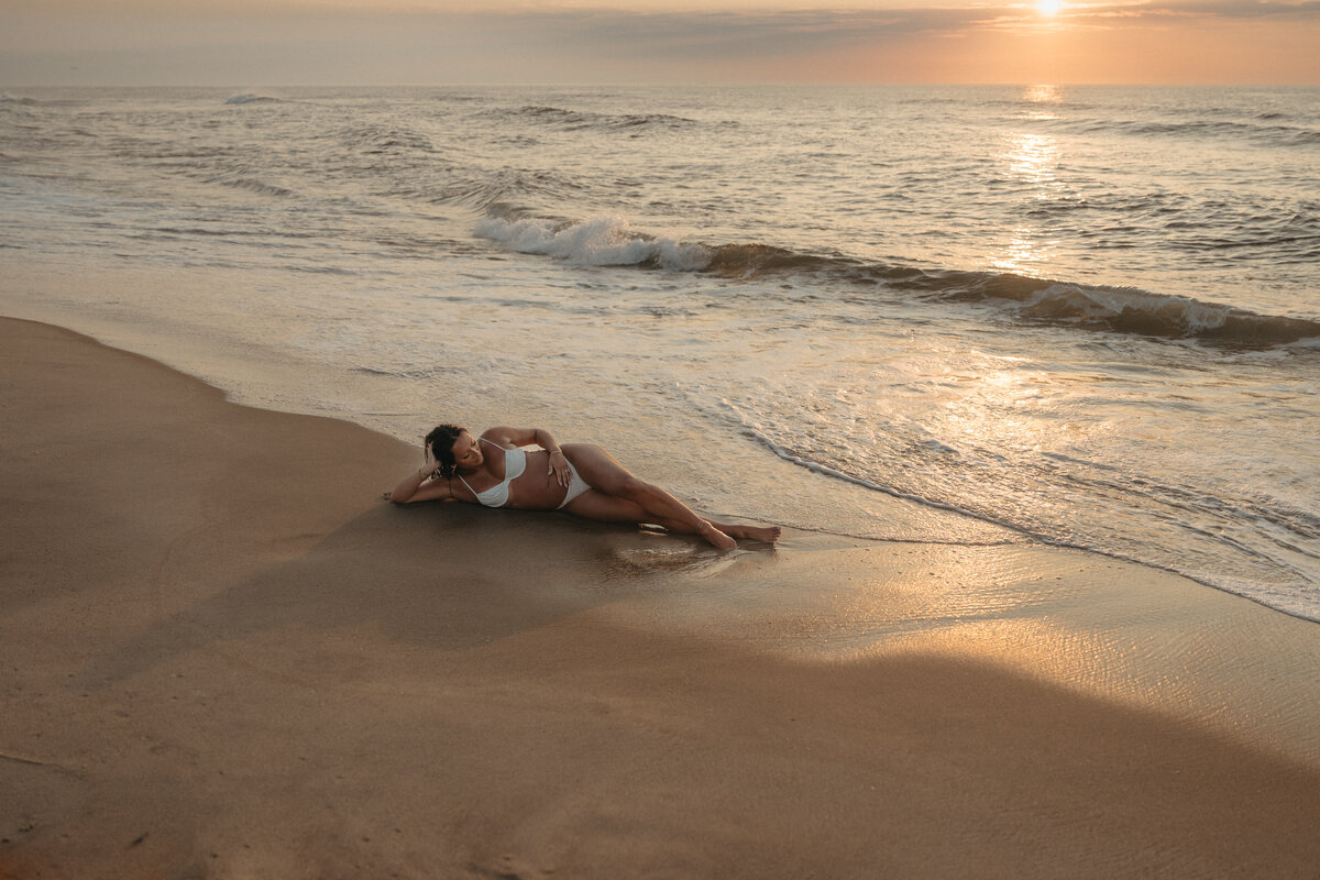 Expecting mom laying on the beach at sunrise