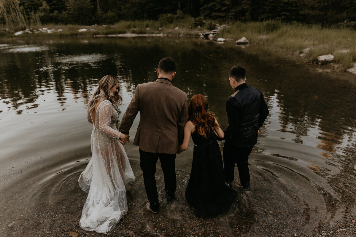 bride and groom walking into a pond with their kids in their formal attire