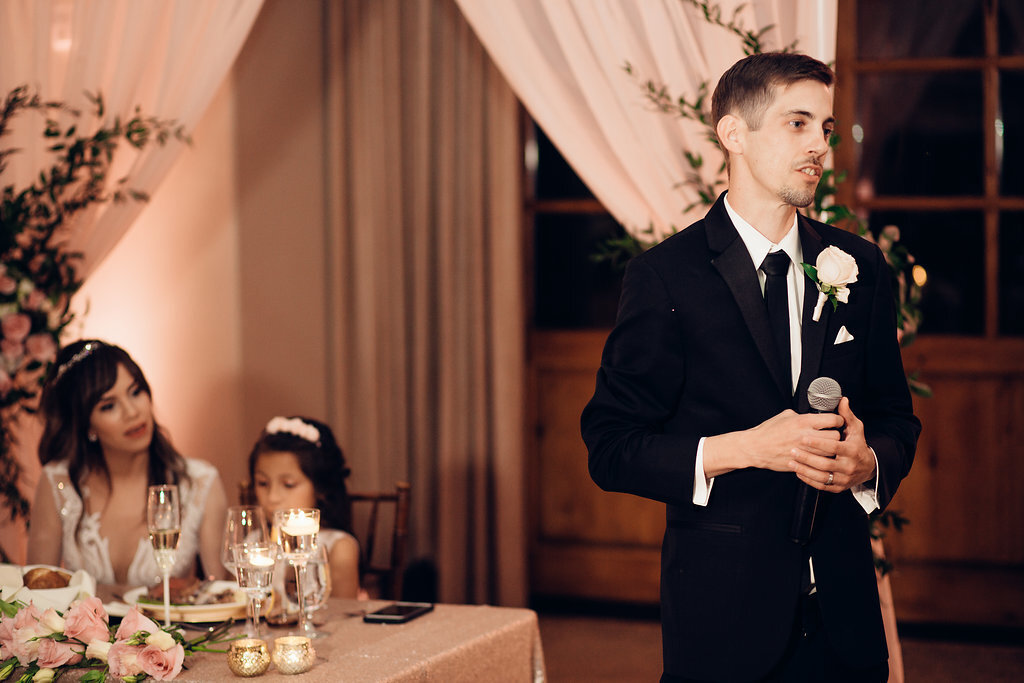 Wedding Photograph Of Groom In Black Suit STanding While Holding a Microphone Los Angeles