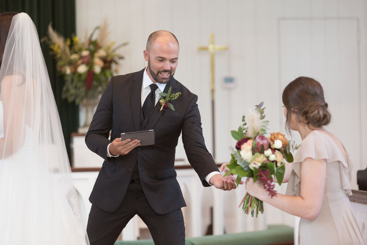 The officiant takes the ring from a bridesmaid during the wedding ceremony at St. Francis at The Point in Point Clear, Alabama.