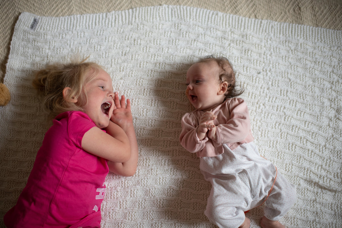 sisters laugh at each other on the floor