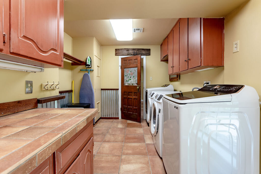 Laundry room with two washer and dryer sets in this 5-bedroom, 4-bathroom vacation rental house for 16+ guests with pool, free wifi, guesthouse and game room just 20 minutes away from downtown Waco, TX.