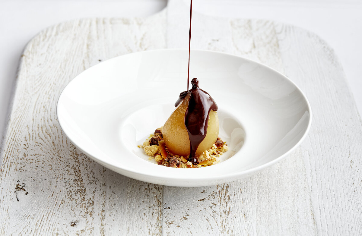 Drizzling dark chocolate on poached pears with a crunchy granola.