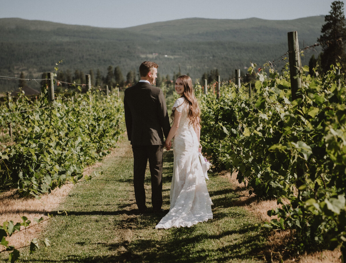 Bride and groom walking through vineyard, captured by Photos by Marissa, nostalgic and romantic wedding photographer in Kelowna, BC. Featured on the Bronte Bride Vendor Guide.