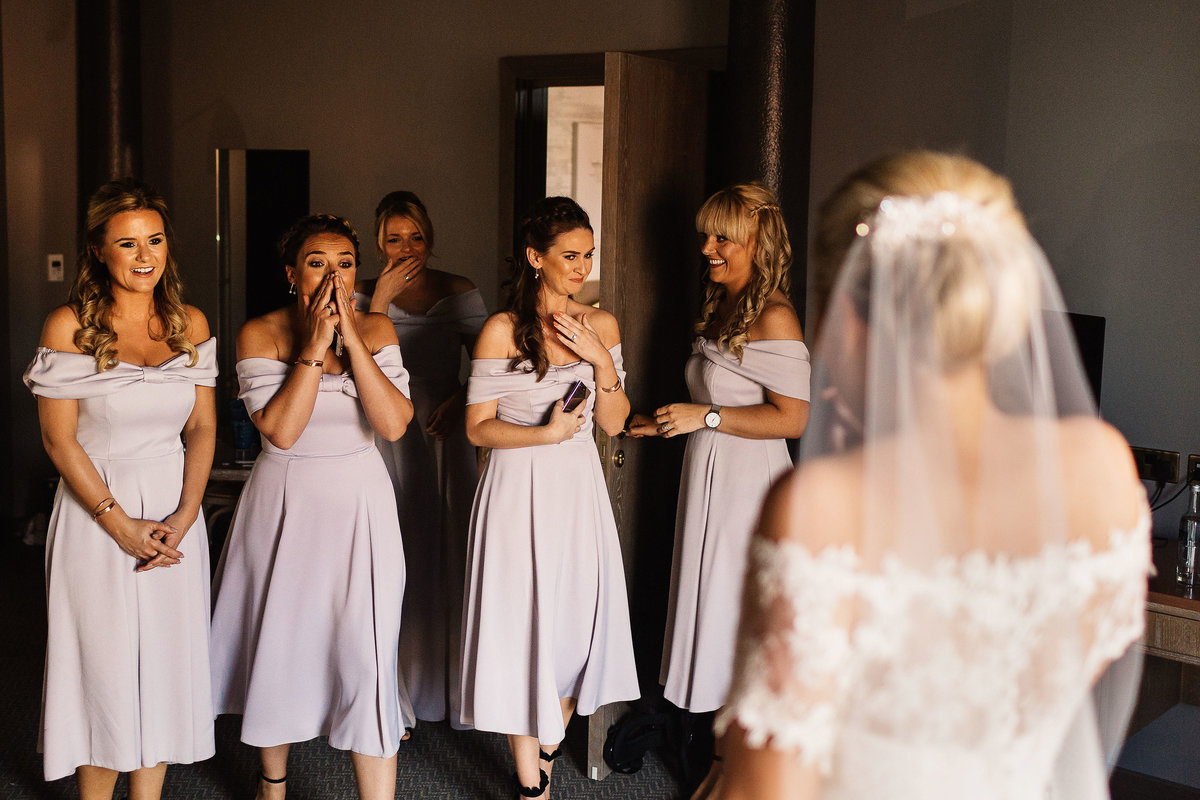 Bridesmaids reacting emotionally after seeing the bride in her wedding dress for the first time