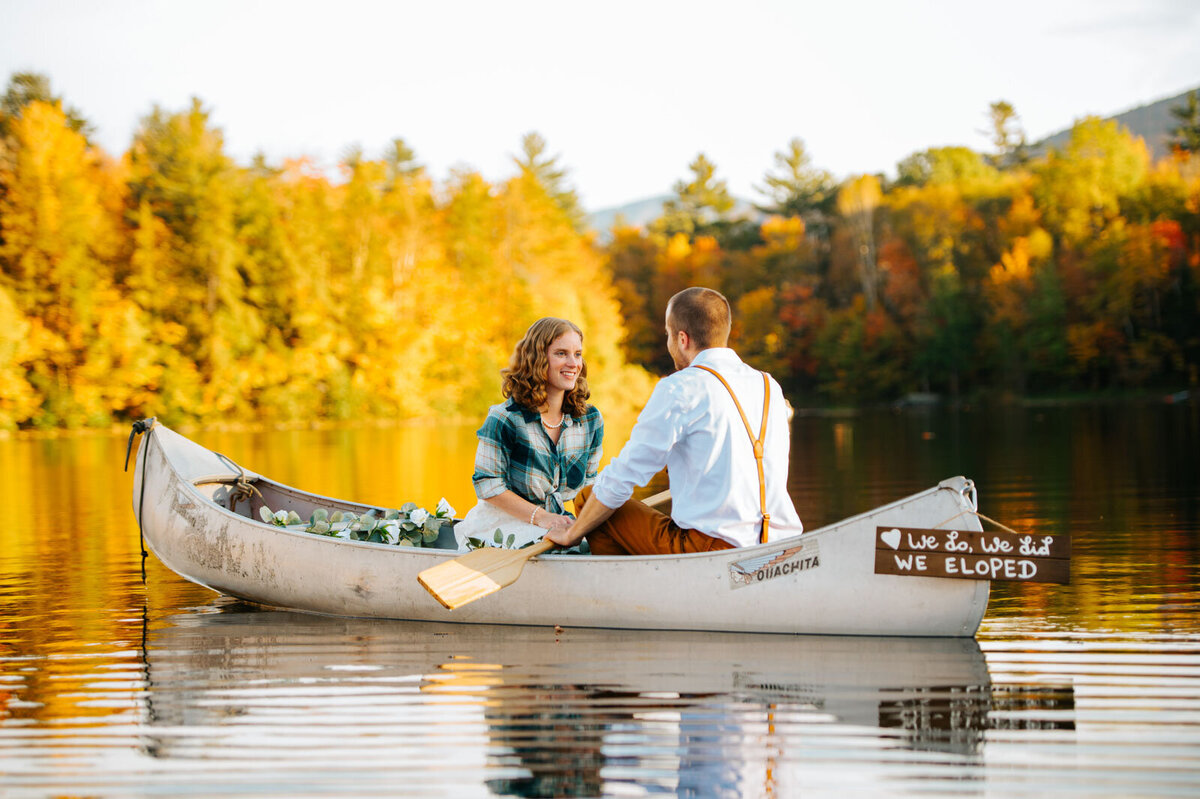 adventure elopement couple in canoe with foliage at chittenden reservoir by mountain top inn in vermont