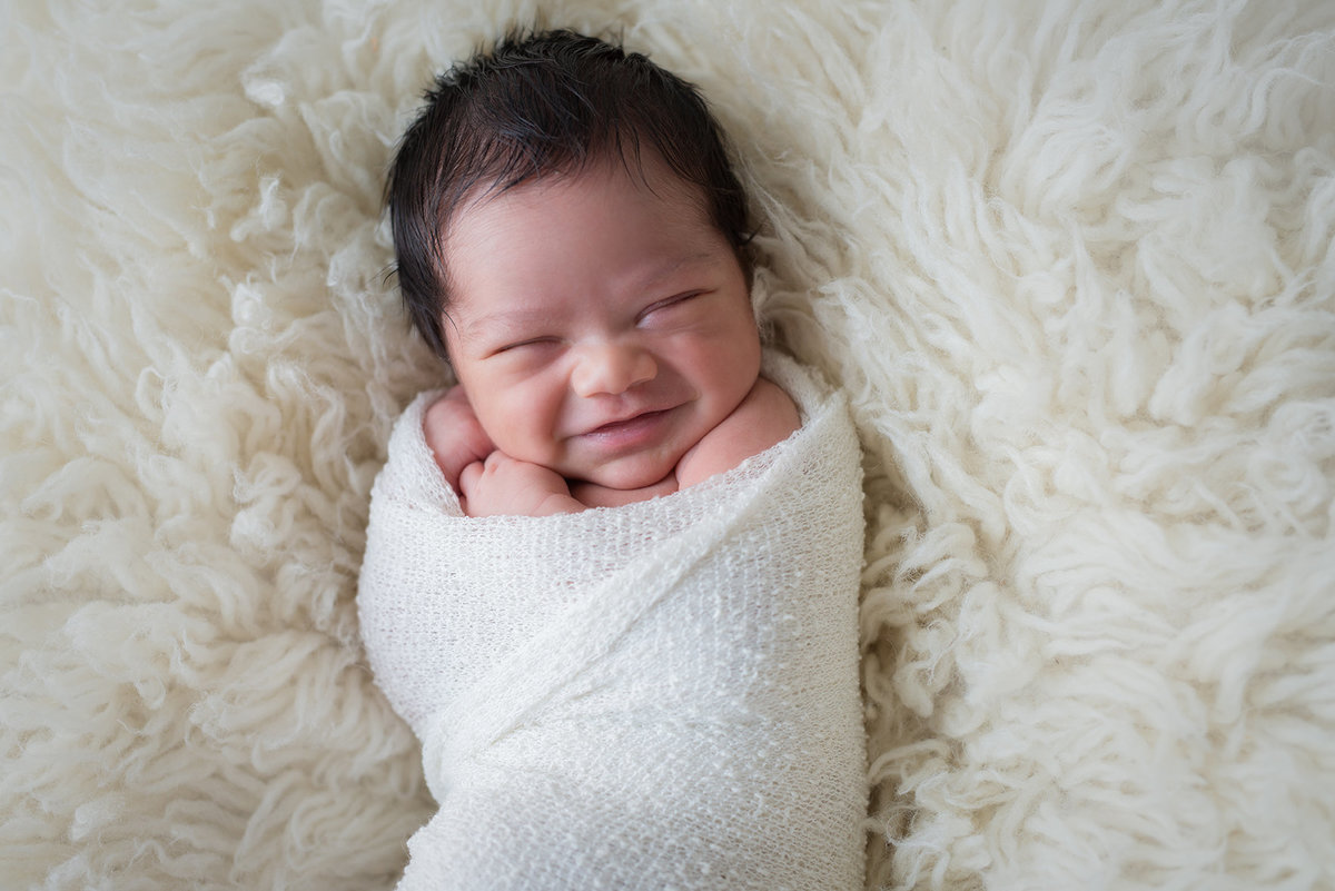 a baby wrapped in white smiling