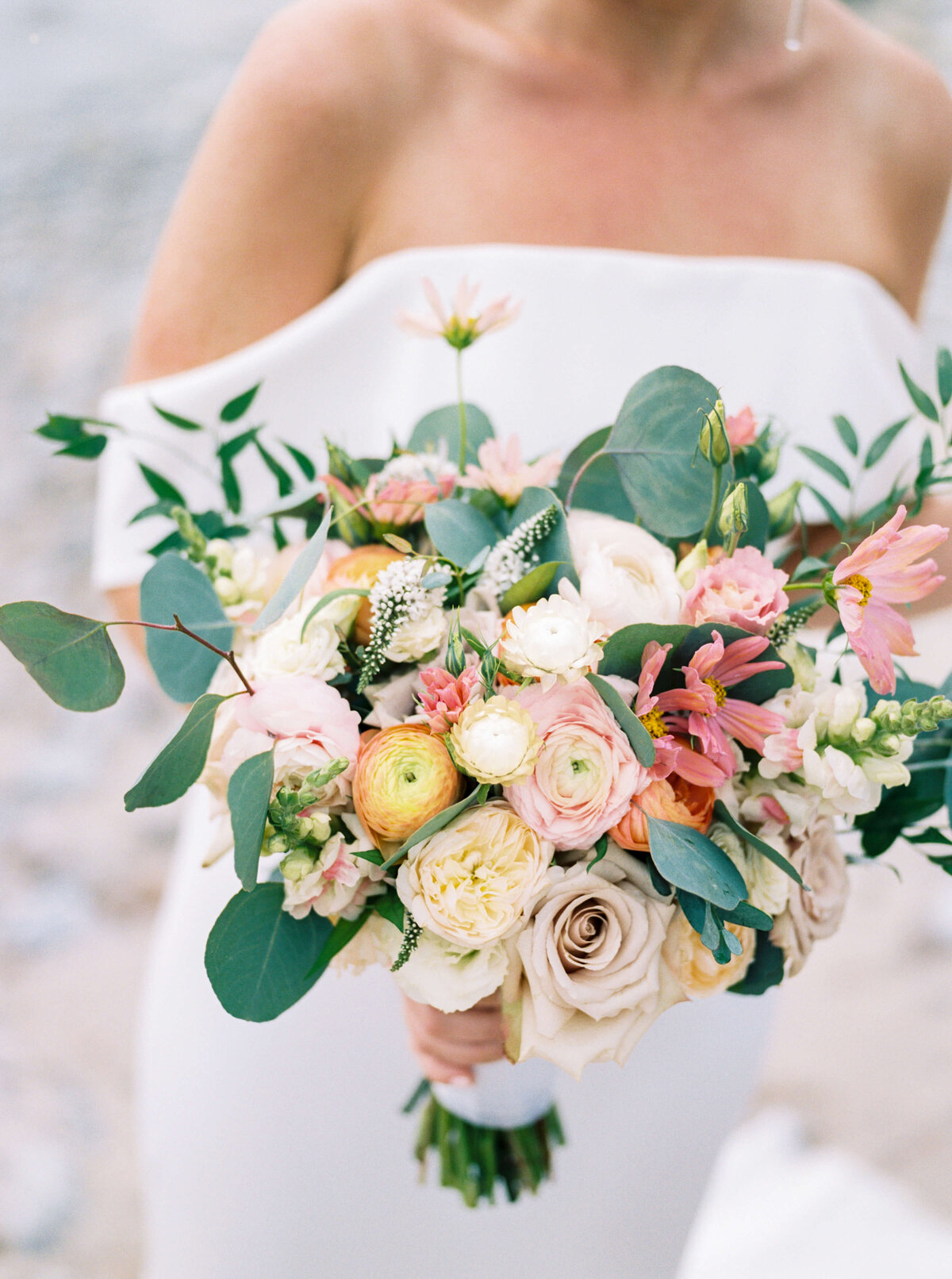 Bride holding colorful bouquet of pinks, yellow and ivory florals