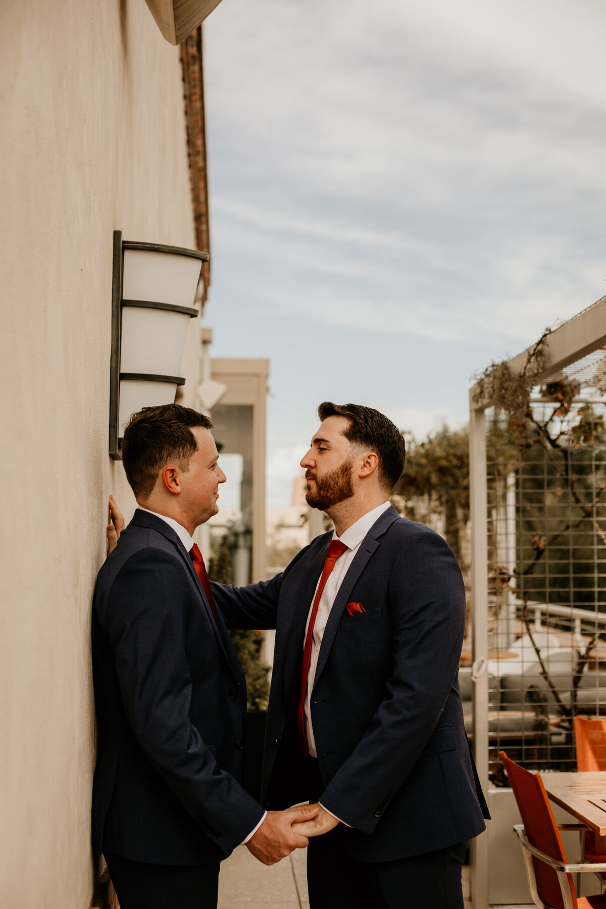 two grooms holding hands on top of a balcony in downtown Albuquerque