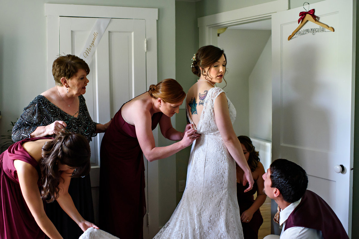 A bridal party helps bride get ready for the outside ceremony at this destination wedding in New Hampshire.