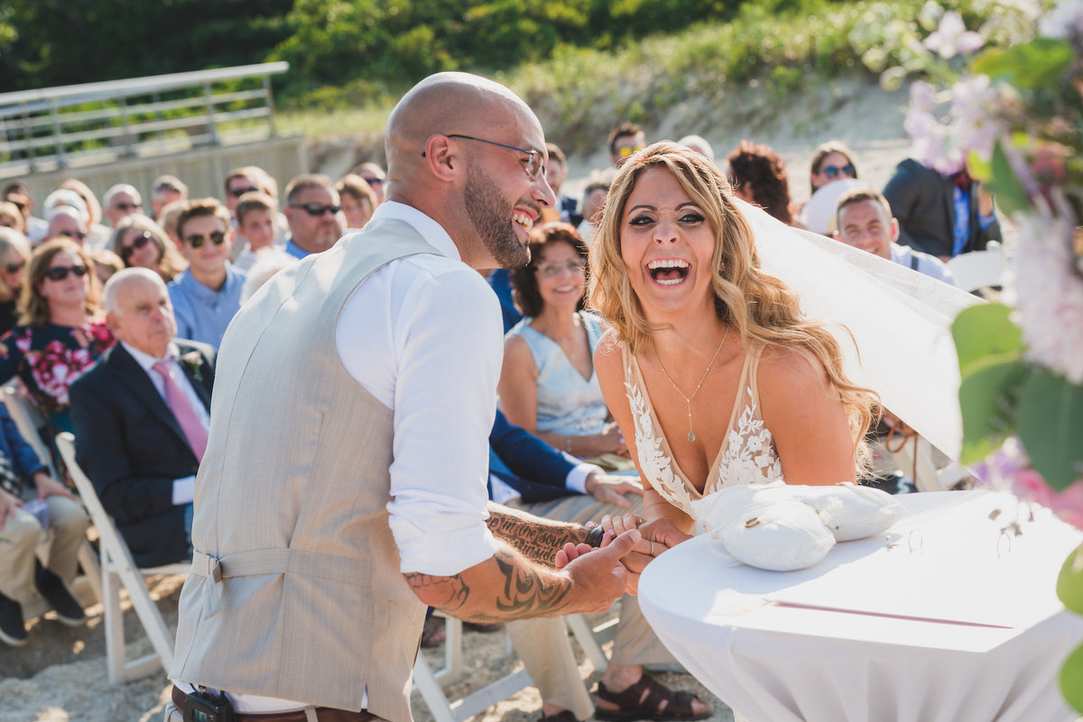 bride and groom laughing during wedding ceremony on the beach at Pavilion at Sunken Meadow