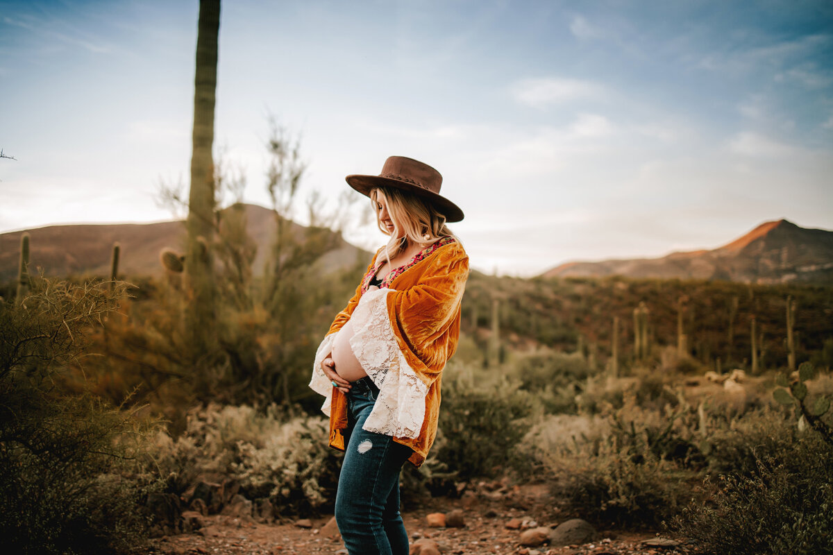 pregnant mom exposes bare belly while wearing a gold duster in the fall in arizona