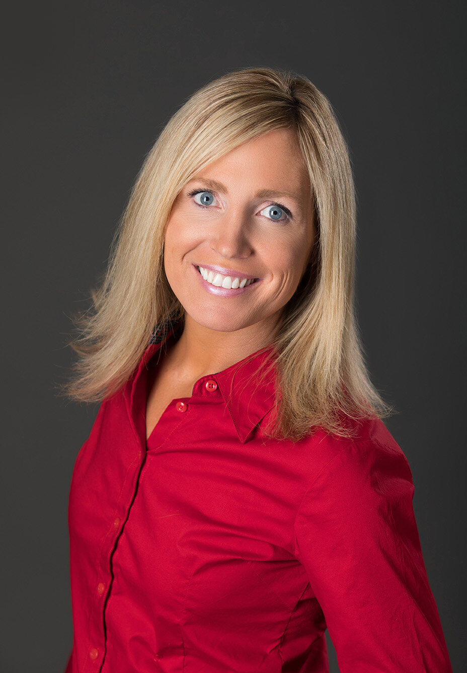 Headshot Jill Bieloh Realtor wearing red shirt on gray backdrop.
