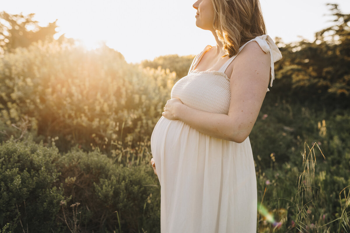Mom at sunset holding her belly Emily Woodall Photography