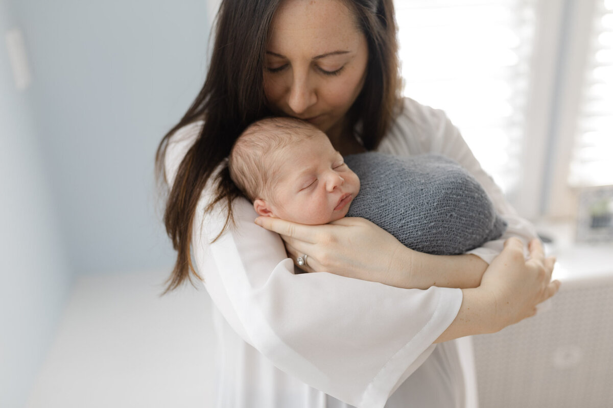 mom holding newborn baby wrapped in blue