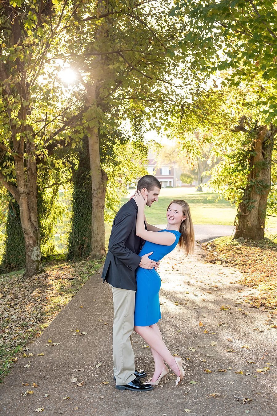 Golden Hour at Smith Park, girl wearing a blue dress and looking at camera while her fiance holds her and smiles down at her