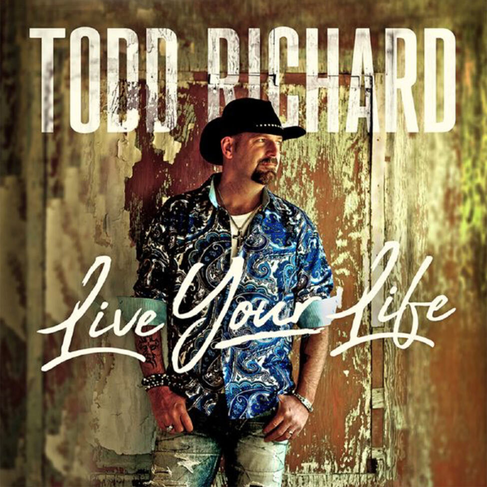 CD Cover Live Your Life Title Country Artist Todd Richard standing in front of rustic wood wall thumbs in pockets of jeans