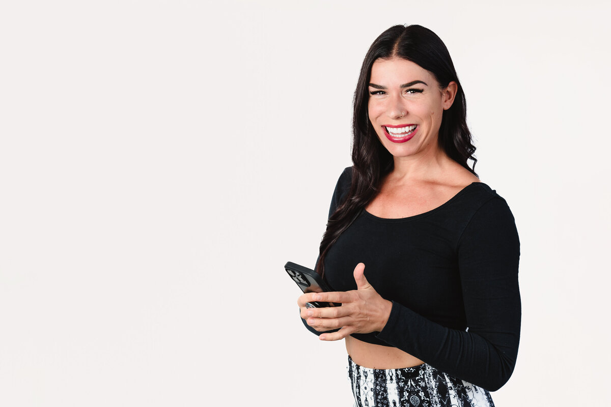 Woman poses for a headshot with her phone on hand