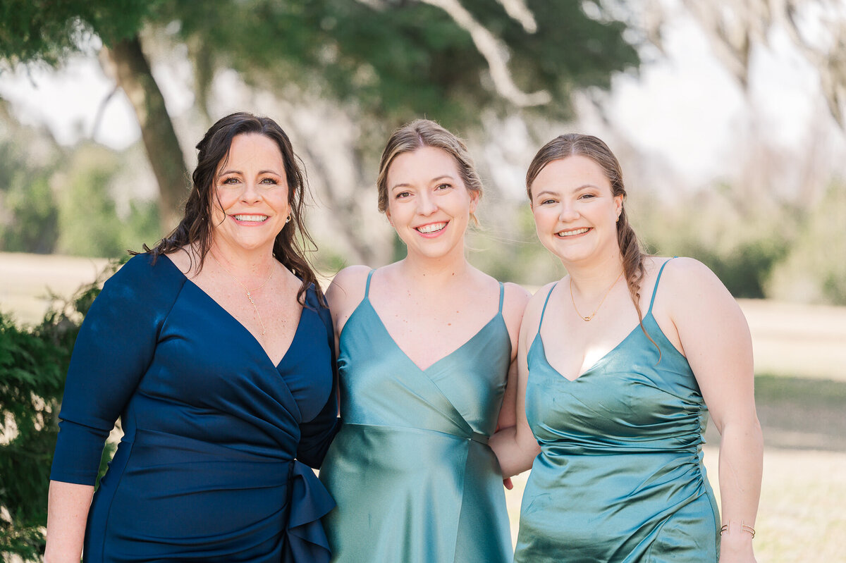 The mother of the bride and two bridesmaids in green and teal dresses
