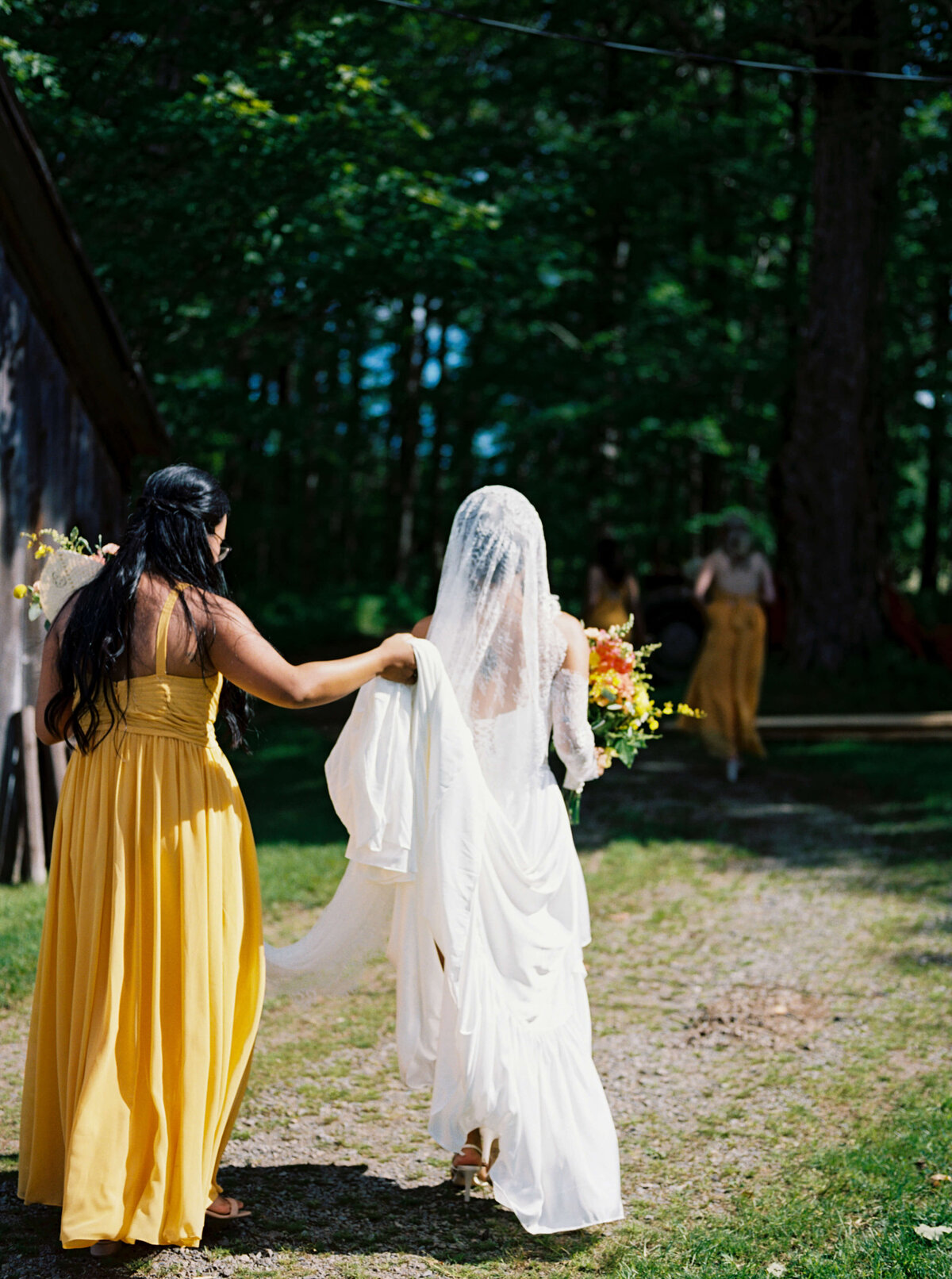 Bride with bridesmaid in yellow dress holding dress up at  Woodburn Ridge Wedding, Nova Scotia