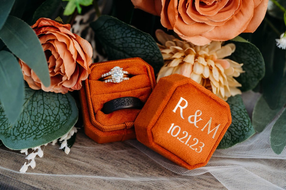 photo of wedding rings in an orange box with the florals