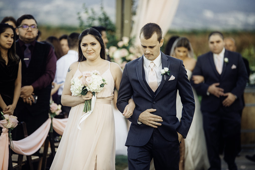 Wedding Photograph Of Bridesmaid And Groomsman Holding His Suit While Walking Los Angeles