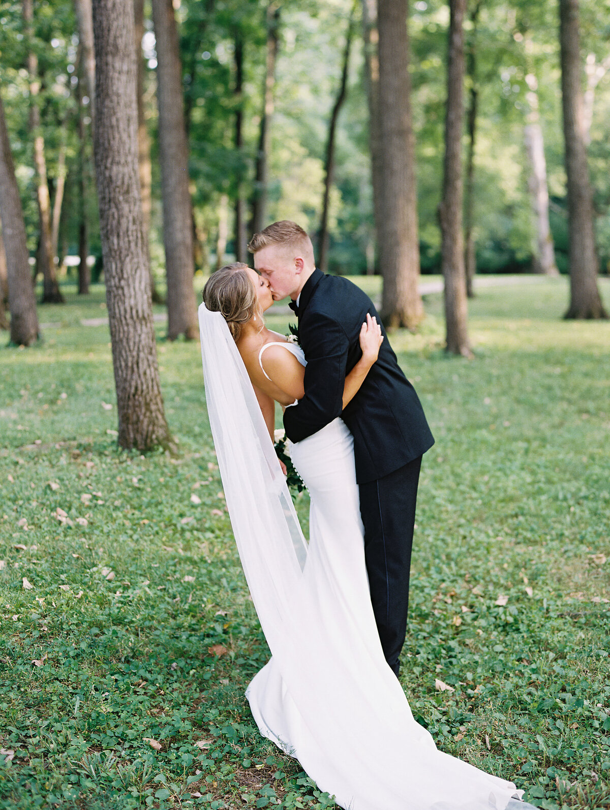 Bride and groom kissing surrounded by trees photographed by Chicago editorial wedding photographer Arielle Peters