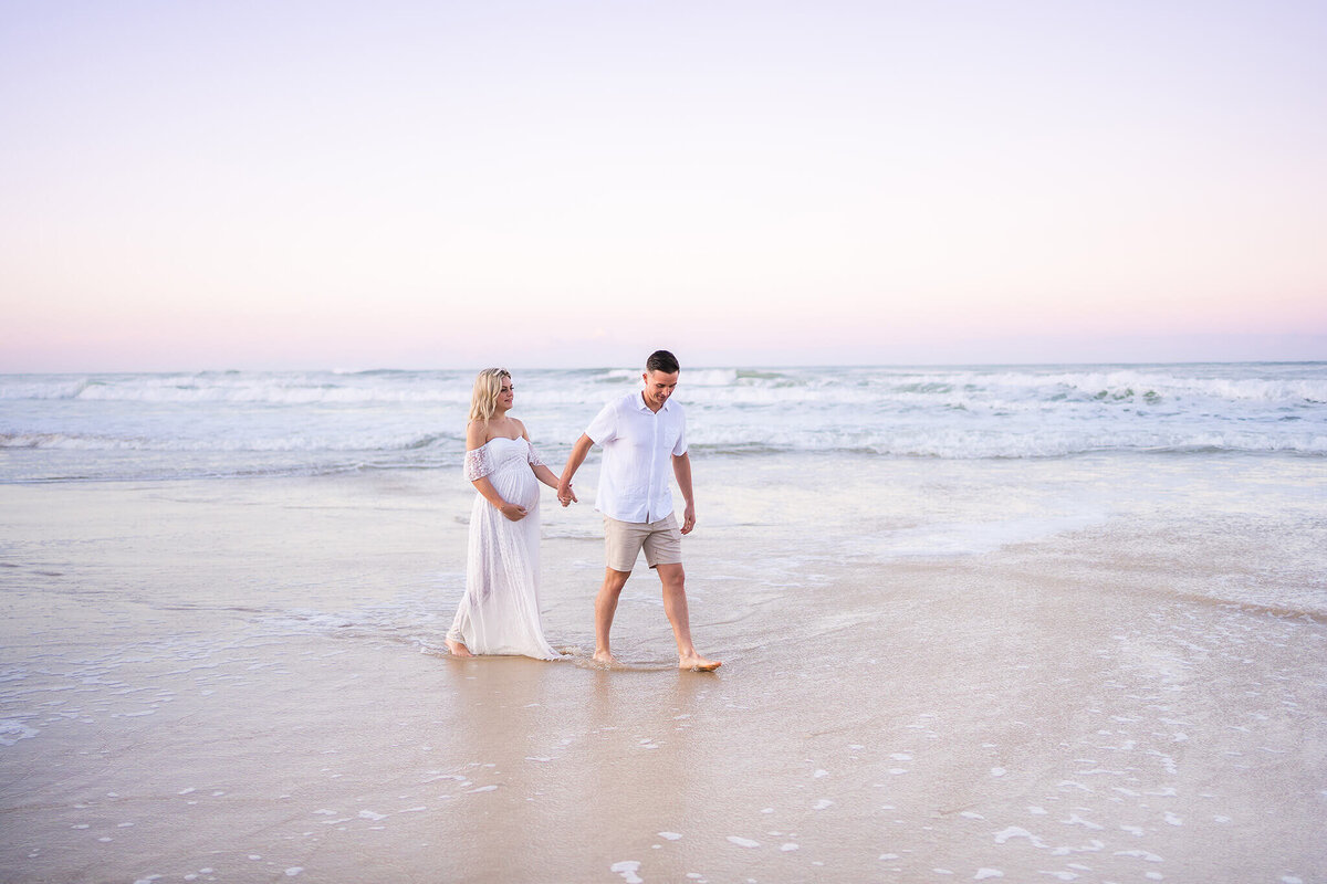 couple running on the beach with pink sky backdrop in Gold Coast