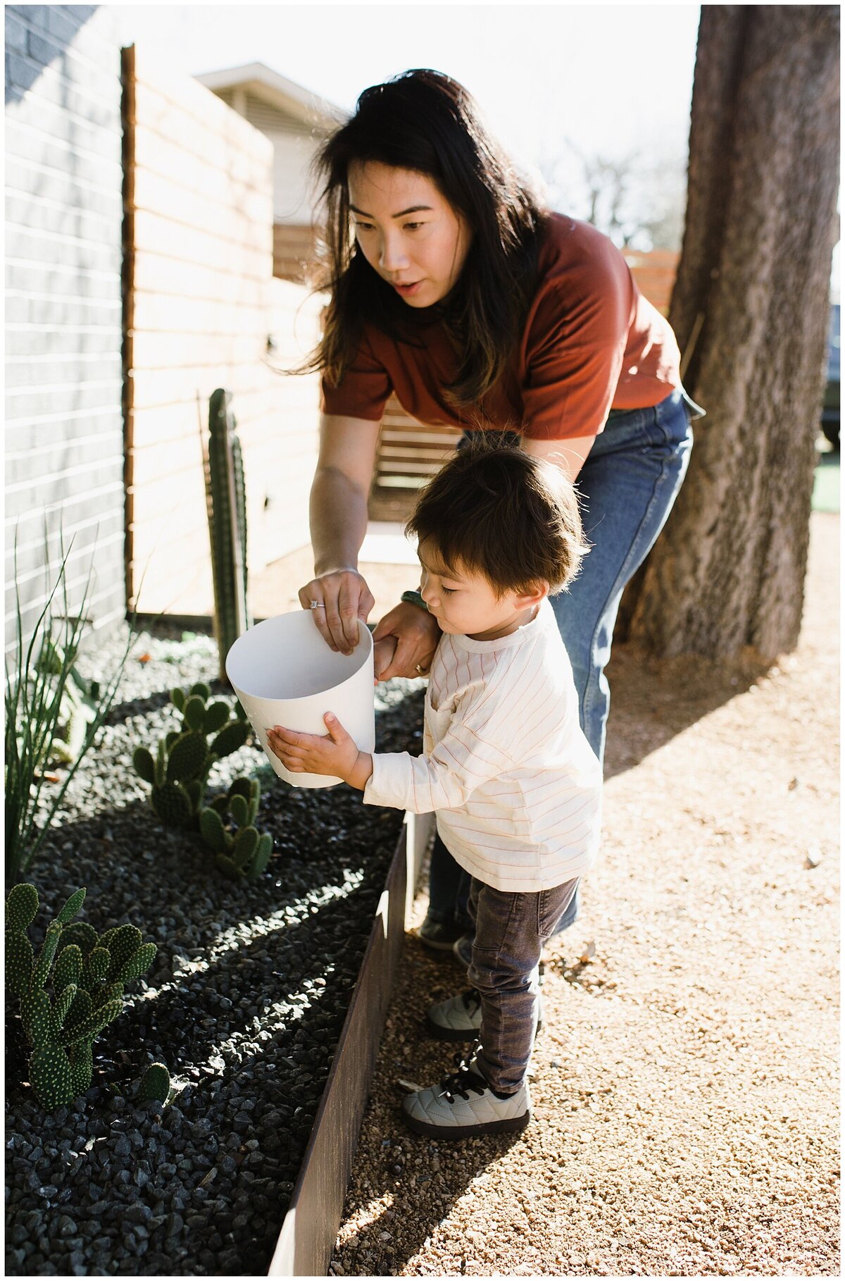 Mother helping child water plants at garden family session in Austin by Amber Vickery Photography