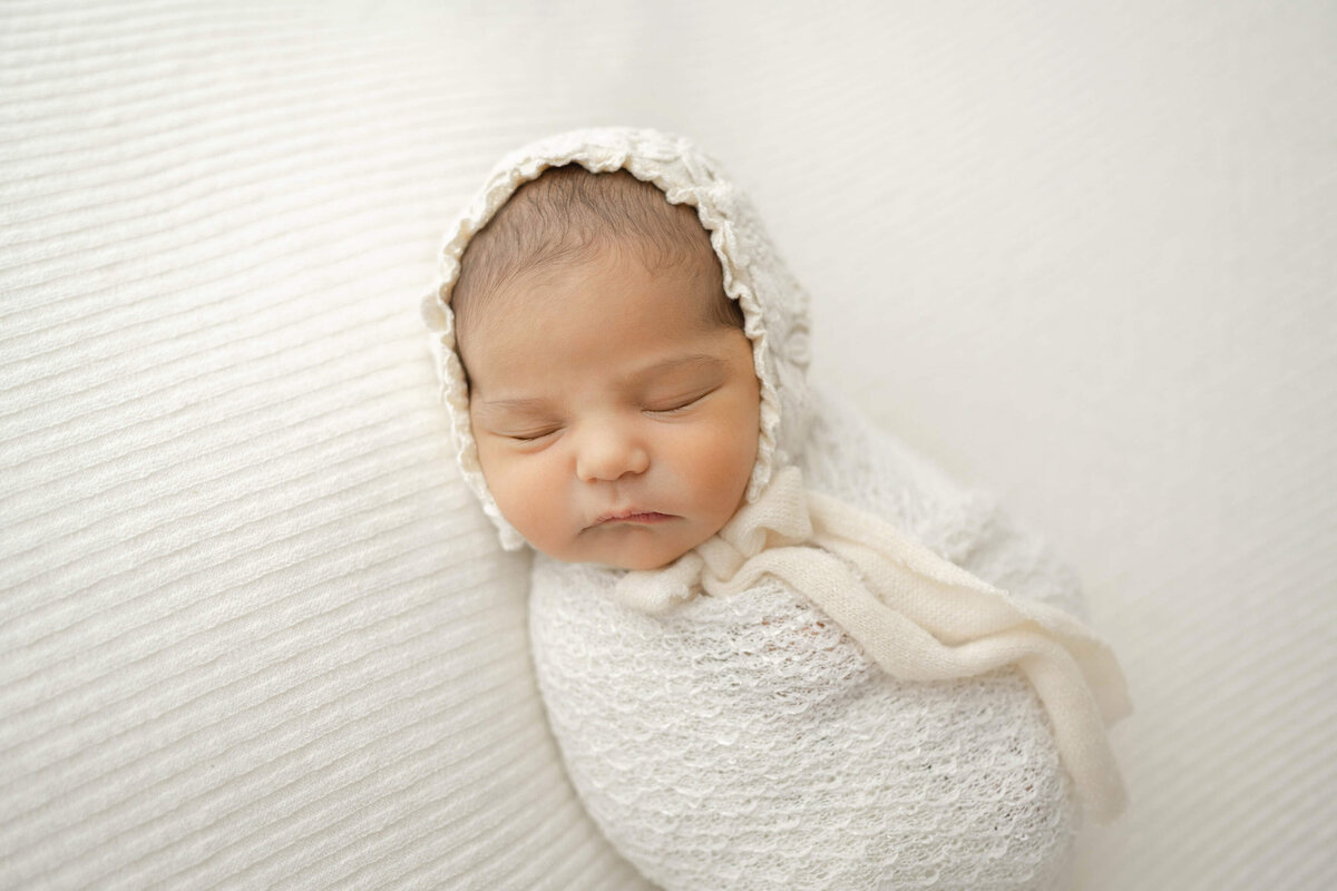 sleeping baby girl wearing a vintage bonnet captured by an okc newborn photographer