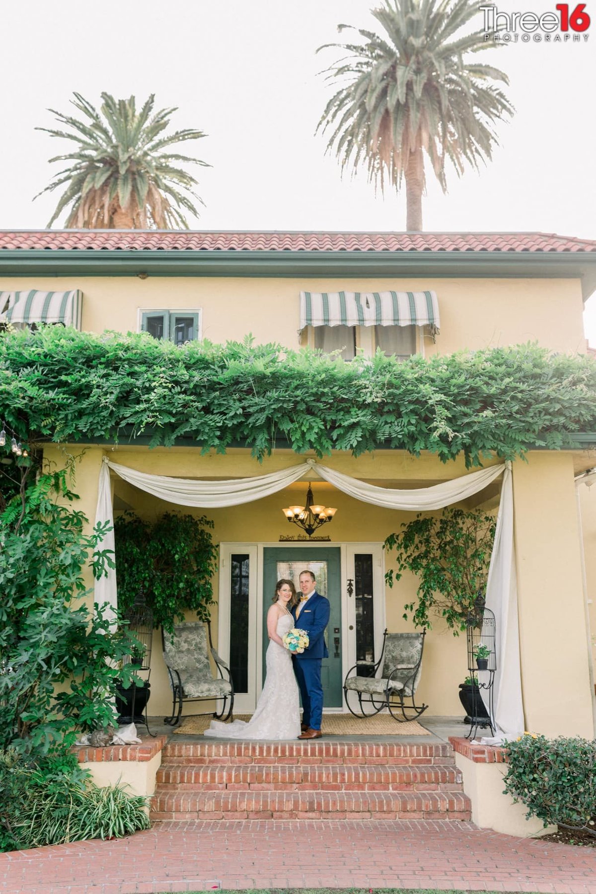 Newly married couple pose together in front of the French Estate wedding venue in Orange, CA