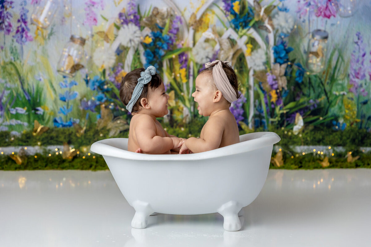 Twins laugh in a bathtub at the first birthday cake smash session in Myrtle Beach, SC