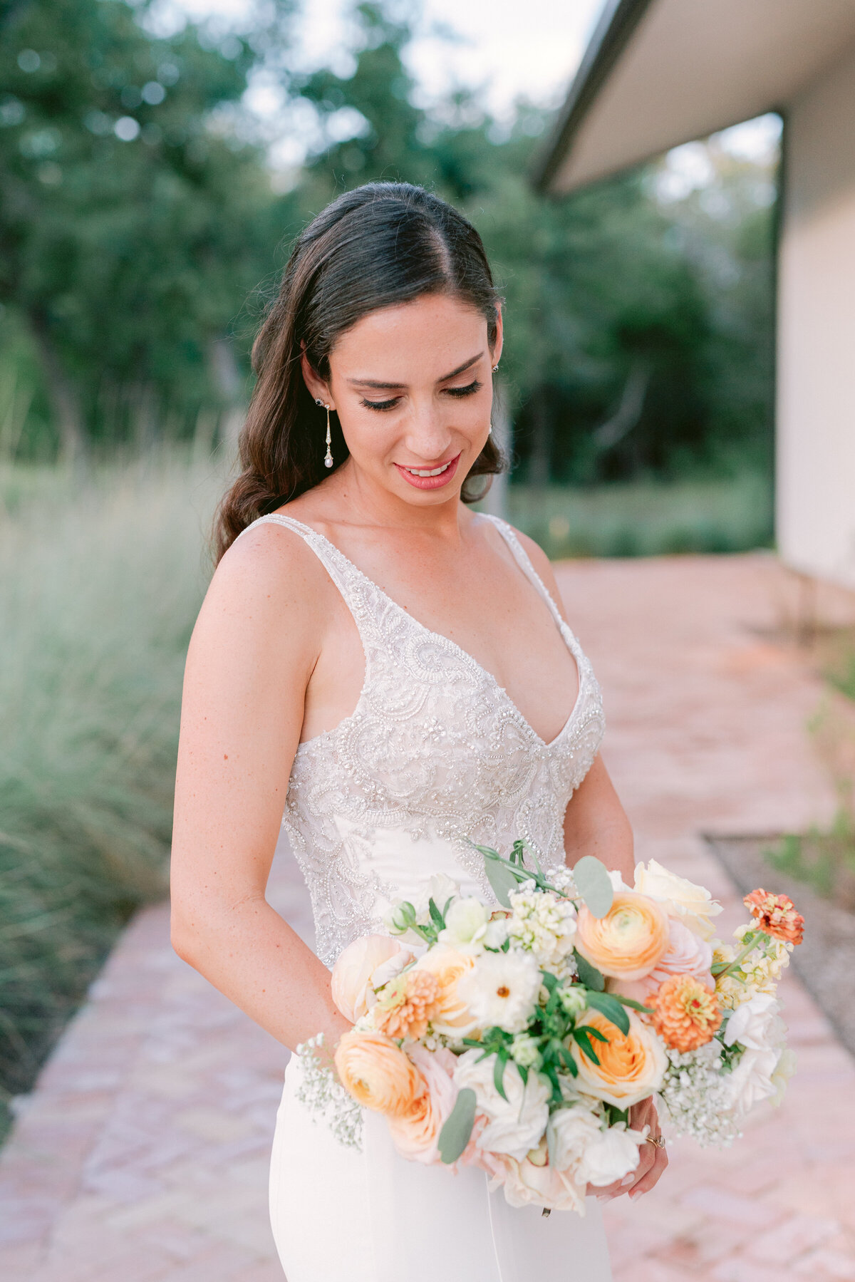 Bridal portraits of bride holding bouquet of white and peach florals in the grounds of The Grand Lady Austin