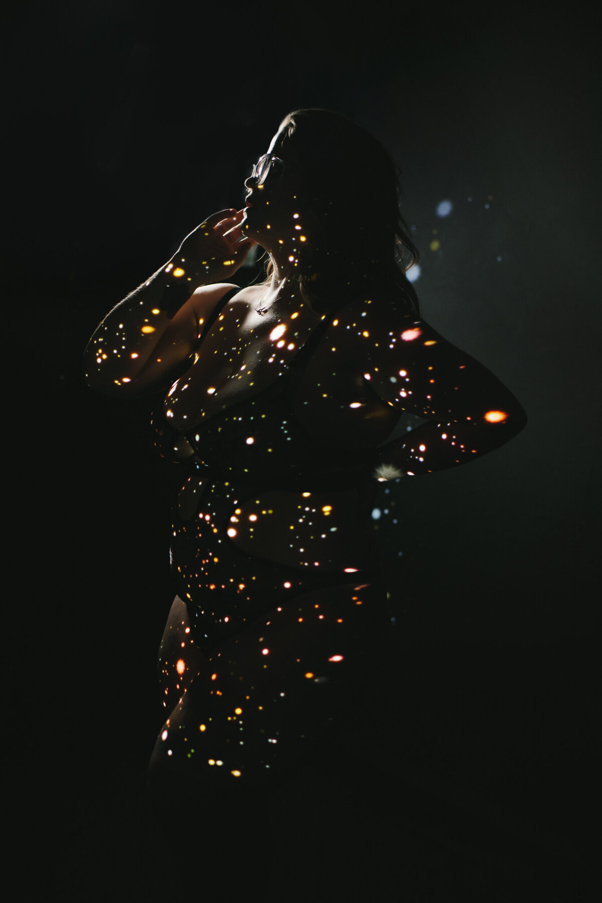 Artistic darkly lit portrait of the silhouette of a woman covered in lights