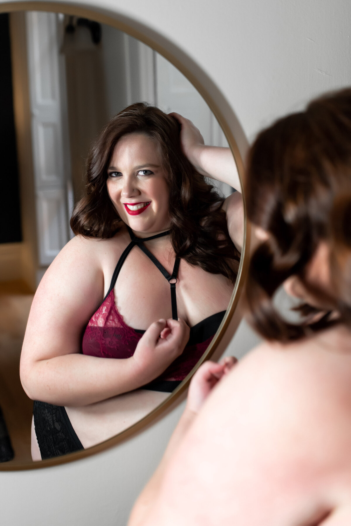 woman posed in a mirror wearing maroon lingerie