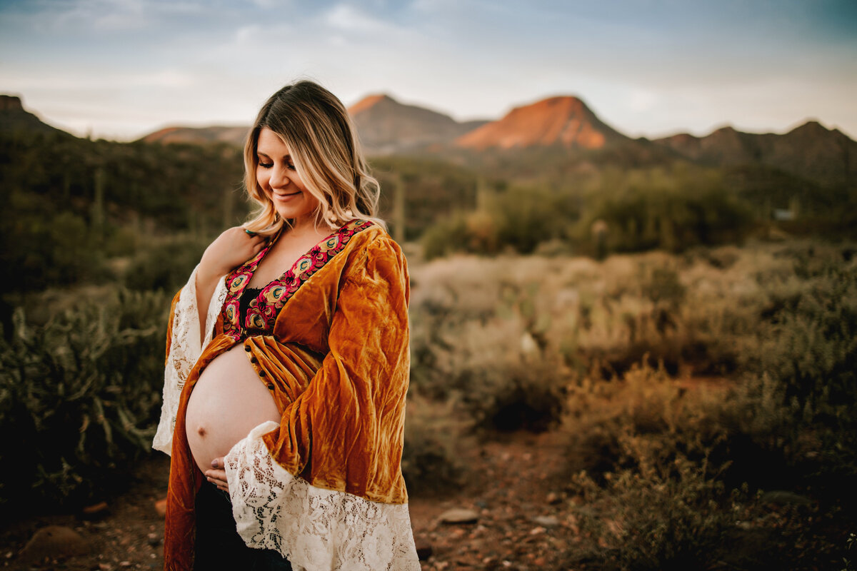 pregnant mom exposes bare belly while wearing a gold duster in the fall in arizona