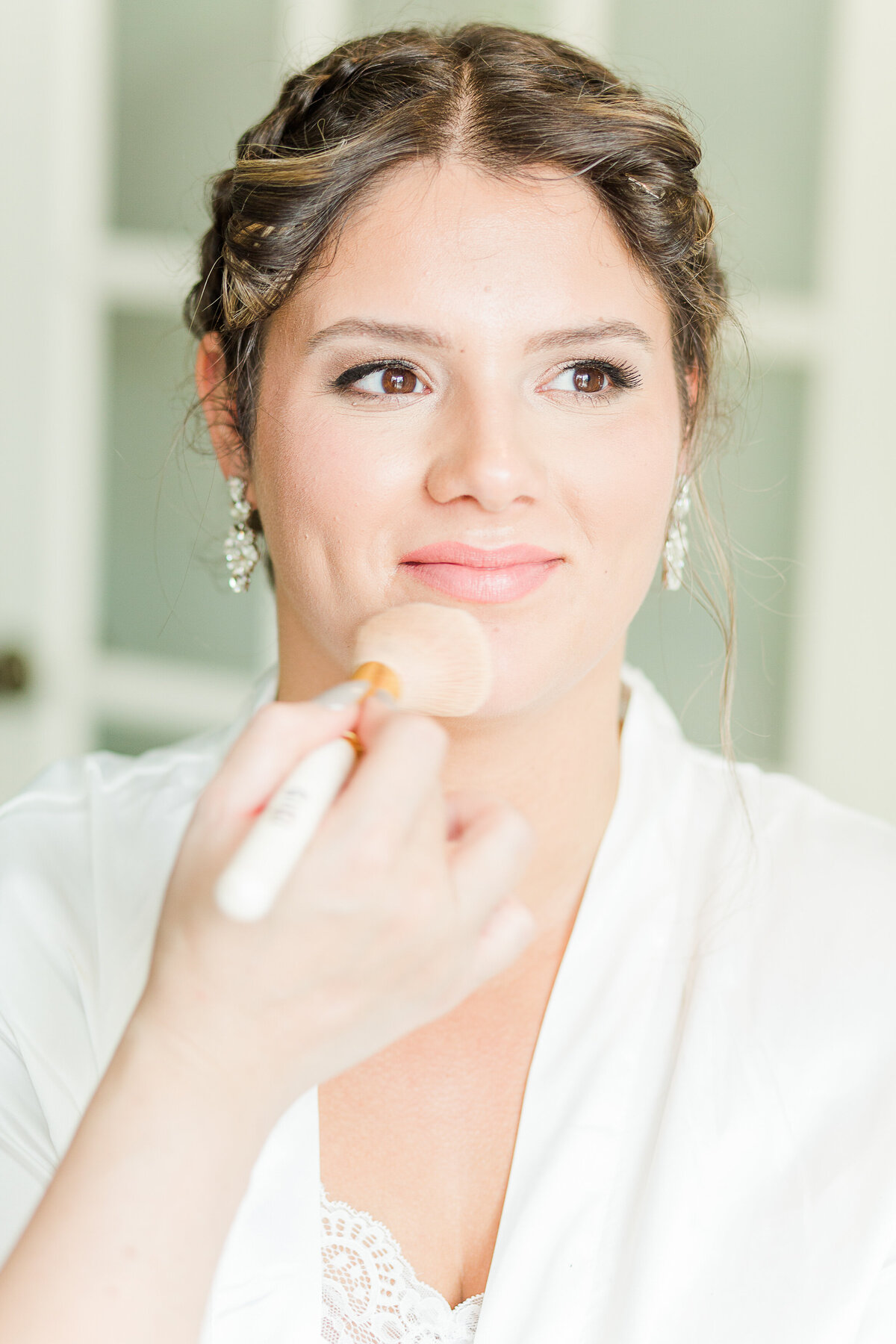 Bride is captured having her makeup applied as she gets ready for her wedding. Captured by Lia Rose Weddings