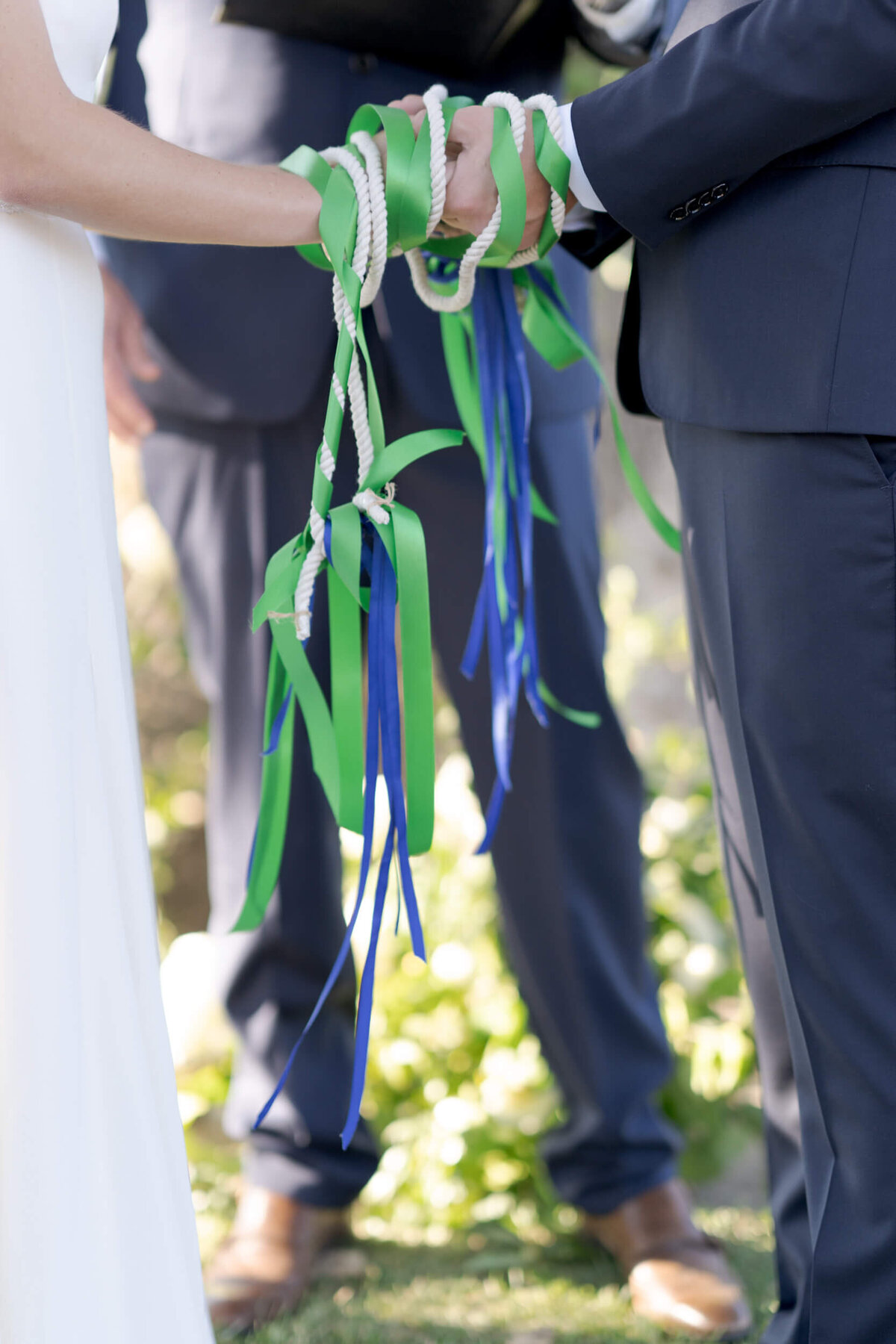 Hands of the marrying couple tied together with ribbons and ropes, symbolizing their unification.