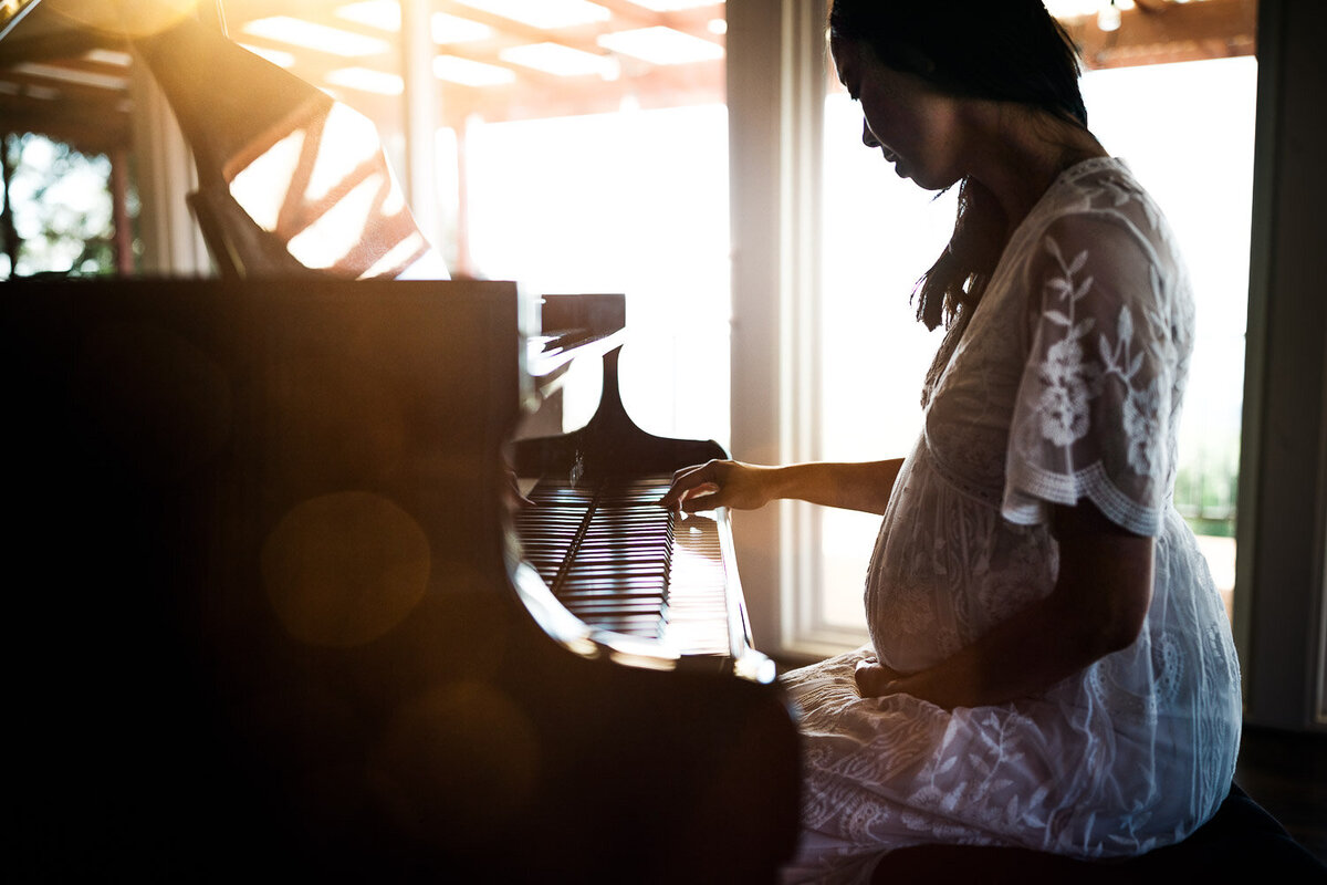 pregnant woman playing the piano during a maternity session at home in oakland.