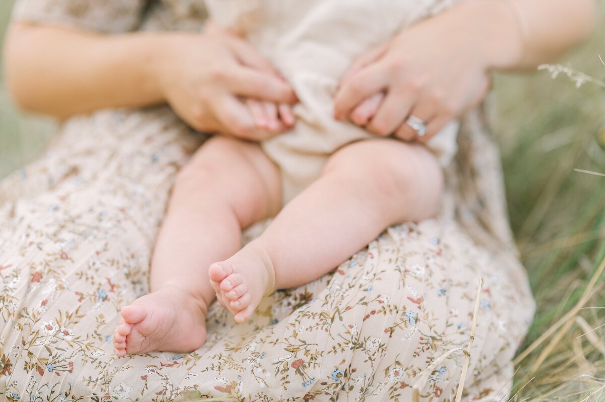 Close up of baby toes and mom holding baby hands