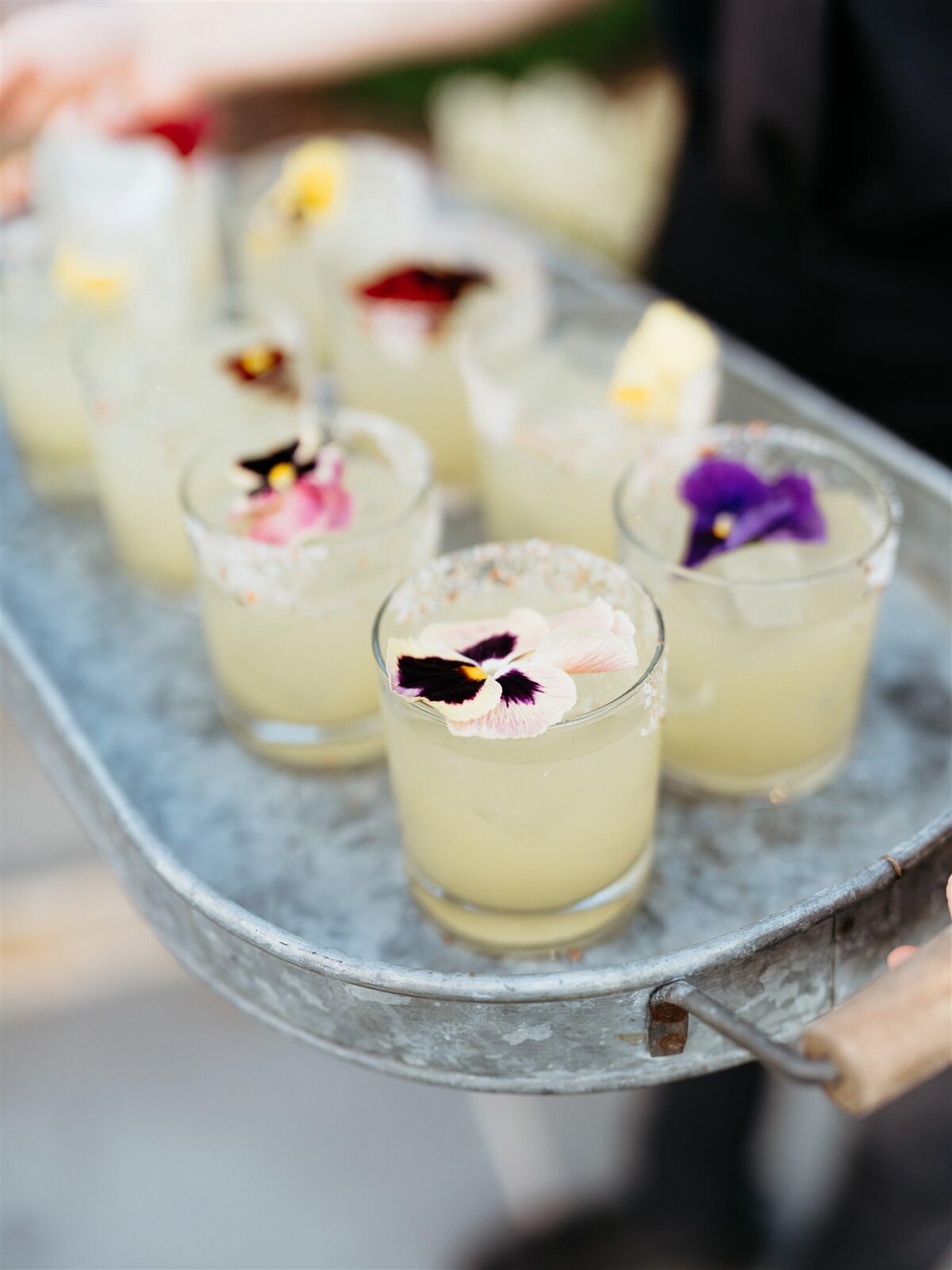 Closeup of violet-garnished lemonade cocktails in galvanized steel tray at Cedar Lakes Estate wedding venue