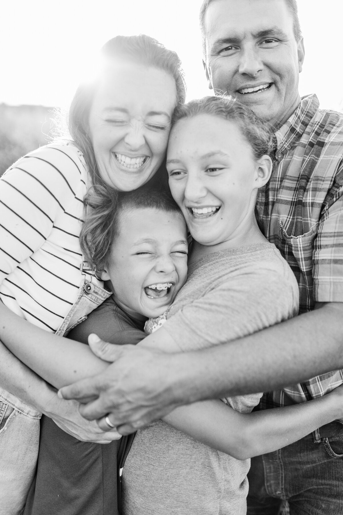 A black and white image of a mom and dad hugging their daughter and son during a family photo session in Lexington KY.