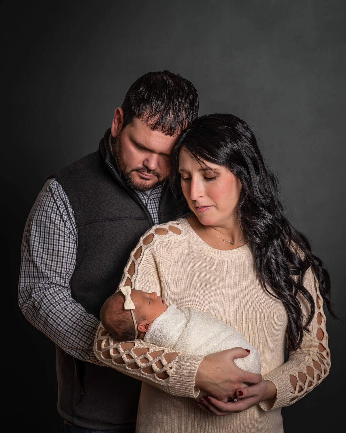 A new mama and daddy hold their newborn baby girl  during their portrait session with an Asheville Newborn Photographer