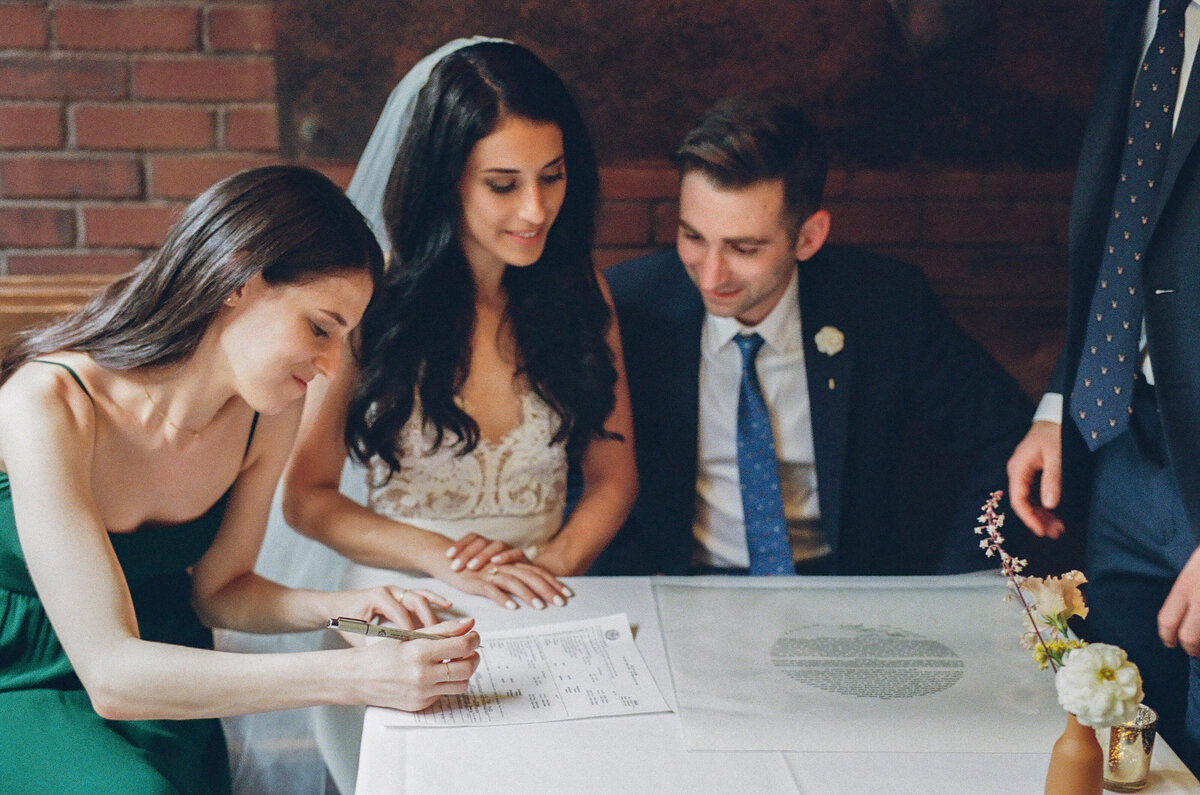 A wedding couple signing their marriage license.