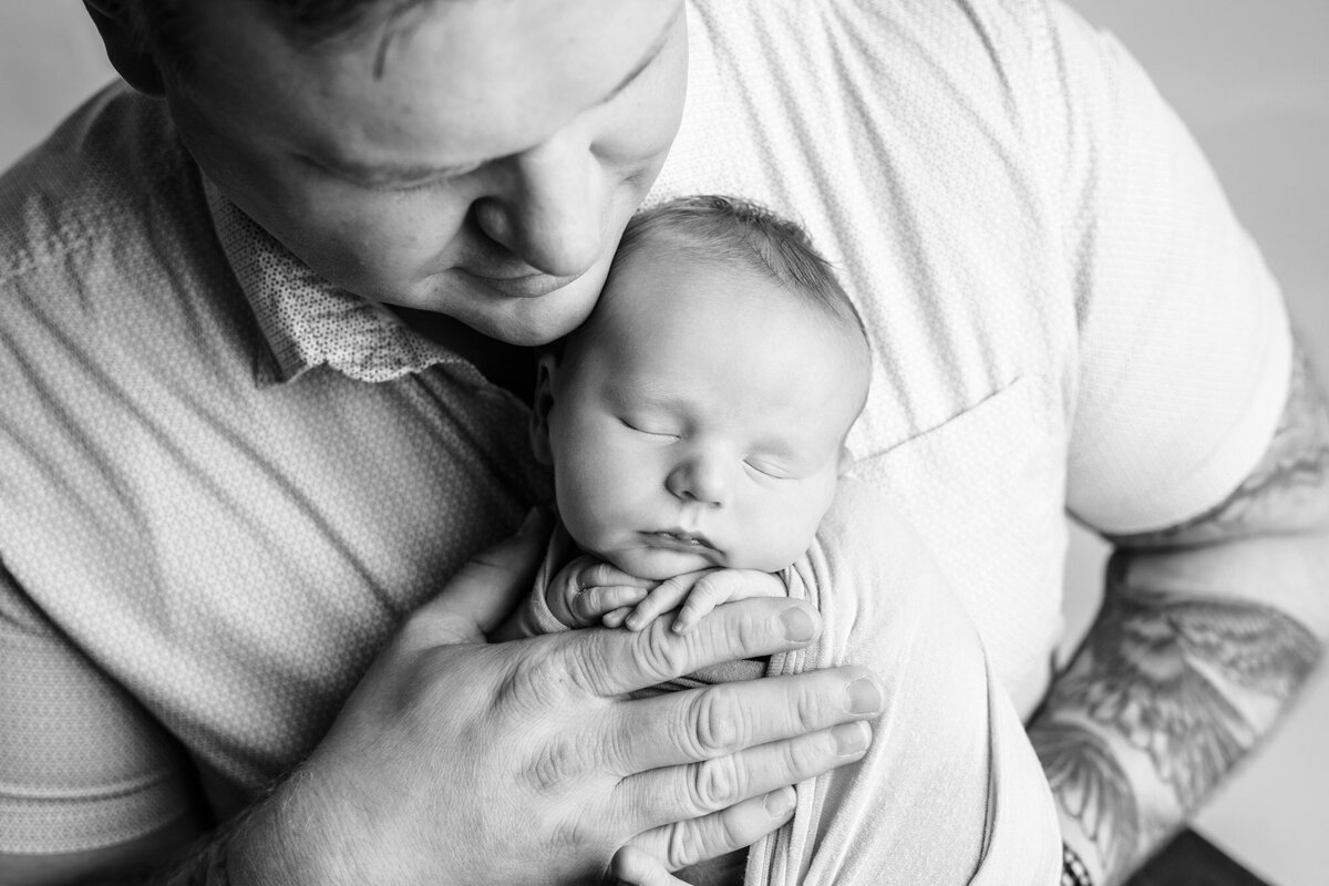 Black and white newborn photo of father holding son