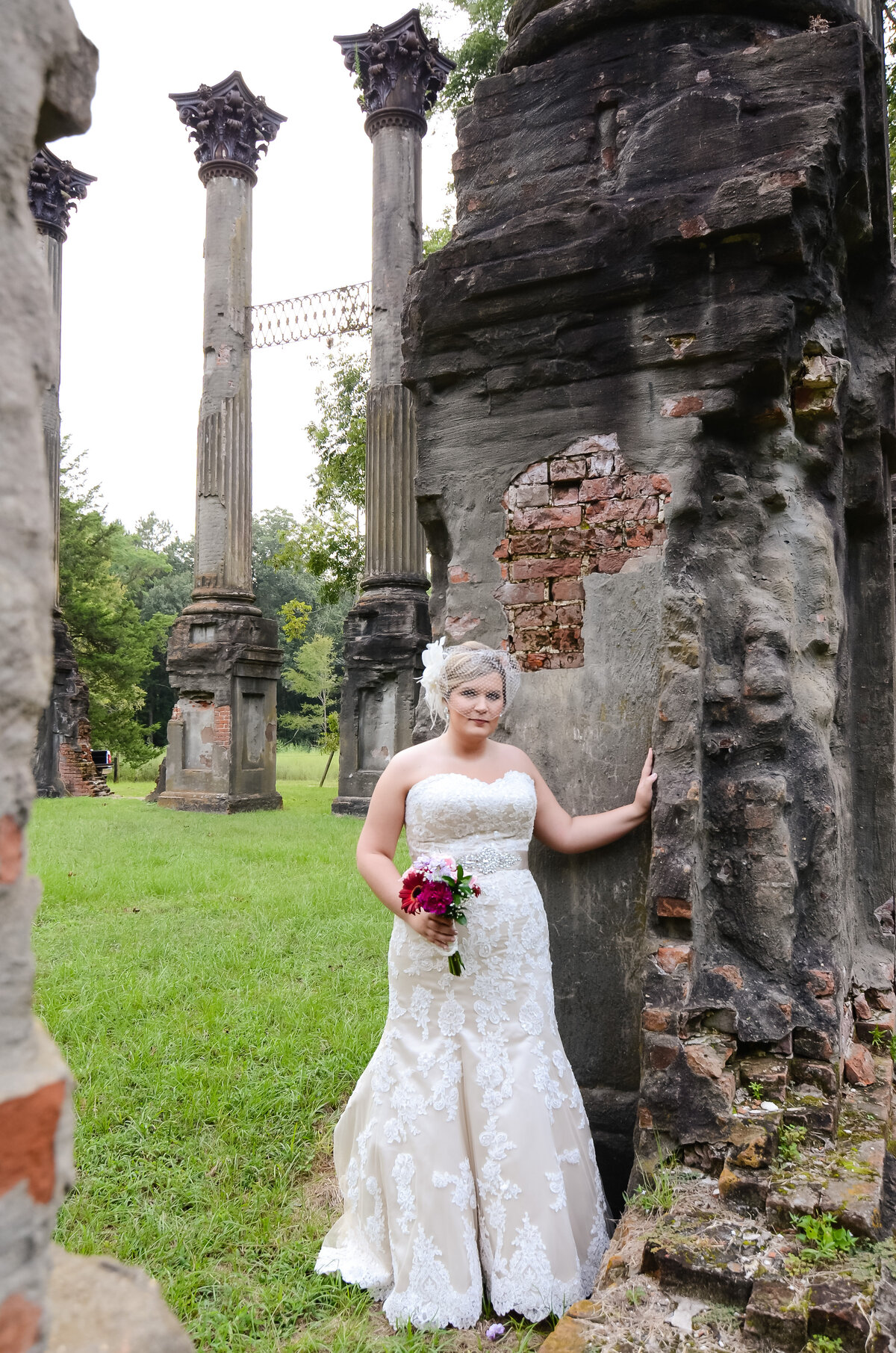 Beautiful bridal portrait photography: Bride with a birdcage veil stands among the ruins at Windsor plantation in MS