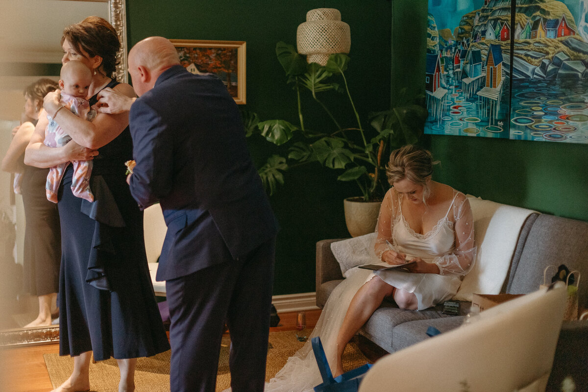 Bride writing her vows while parents care for the baby