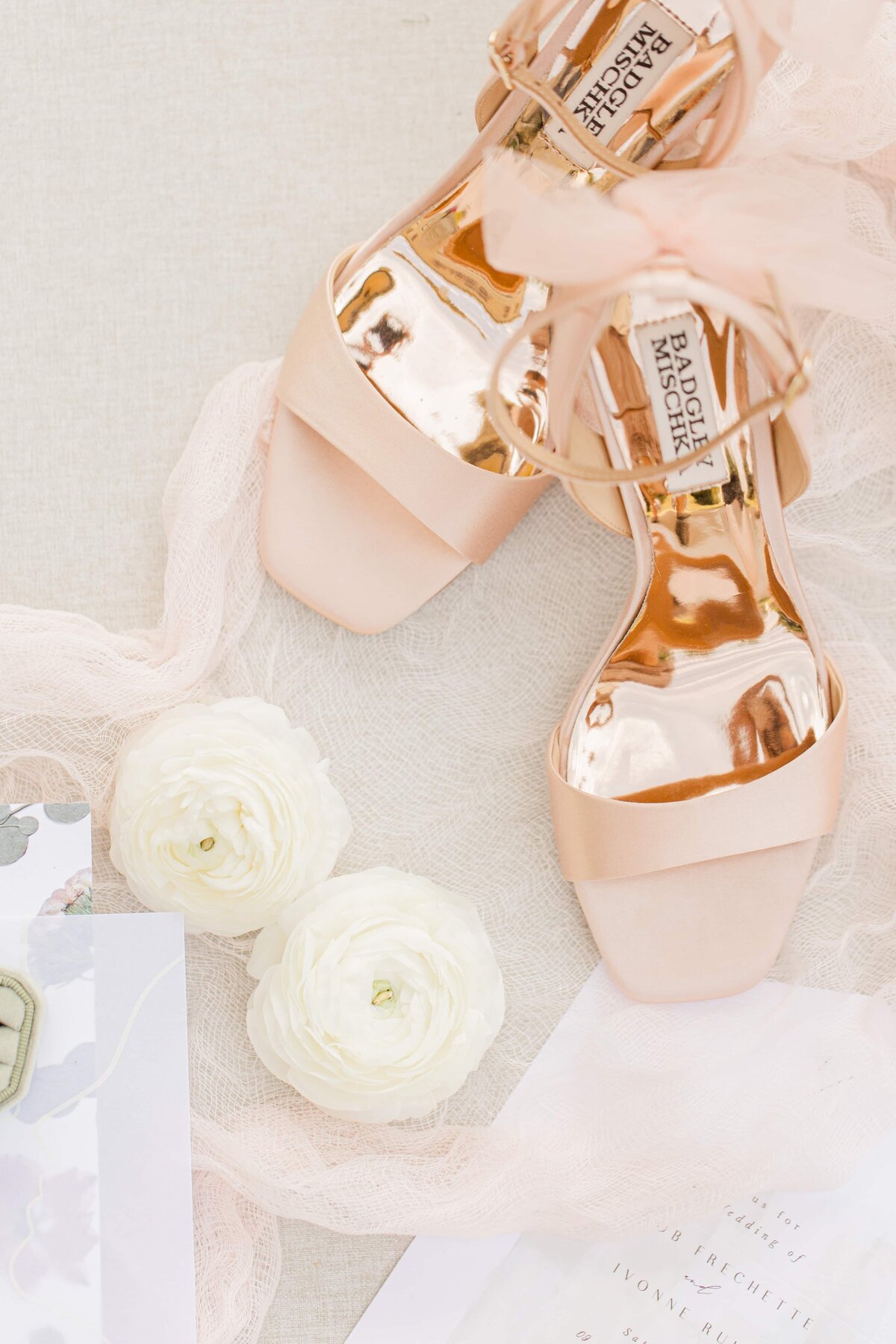 Elegant rose gold high-heeled shoes with ribbons, surrounded by white roses and wedding stationery on a light background, perfect for Park Farm Winery weddings.