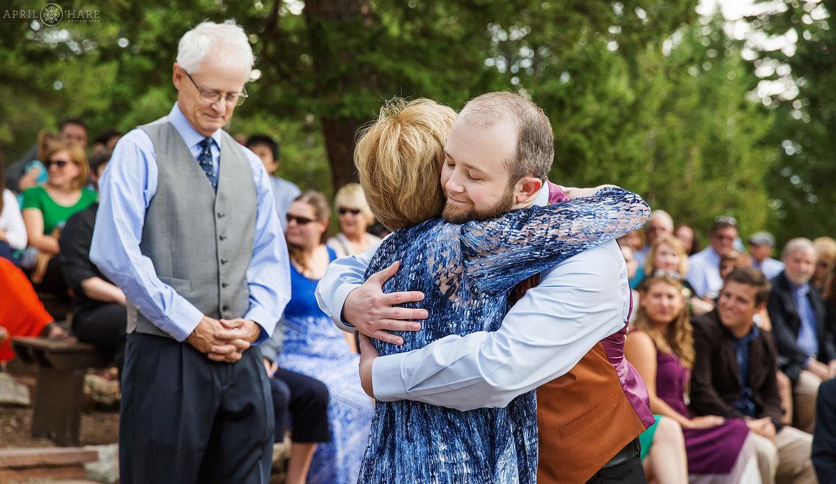Groom hugs mom at outdoor wedding ceremony at Colorado Mountain Ranch in Boulder