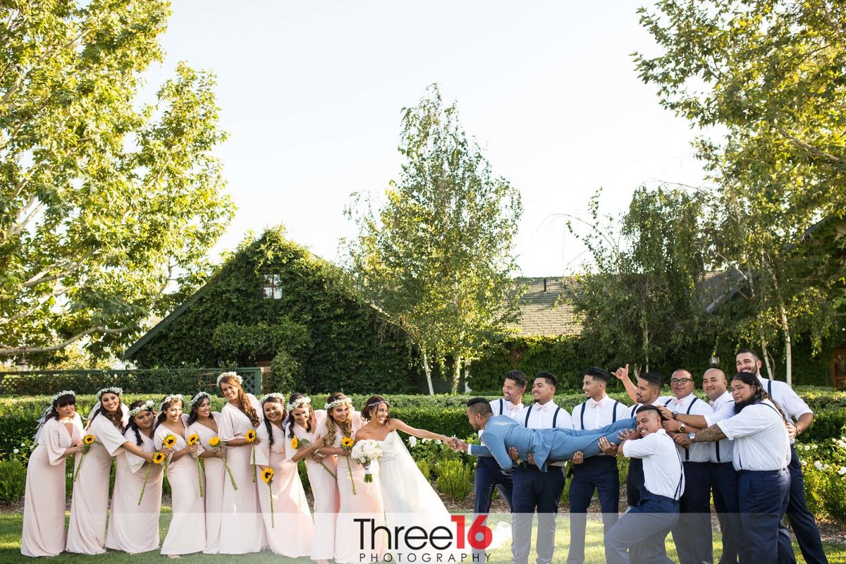 Fun photo of bridal party playing tug of war with the Bride and Groom